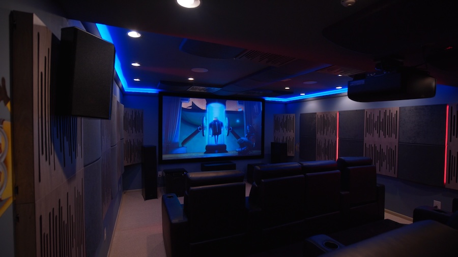 A luxury home theater with blue lighting and the movie “Despicable Me” on screen.