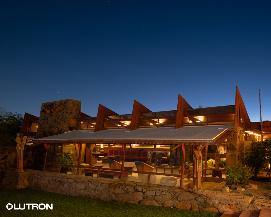 The exterior of Taliesin West, a Frank Lloyd Wright house, illuminated in warm lighting.