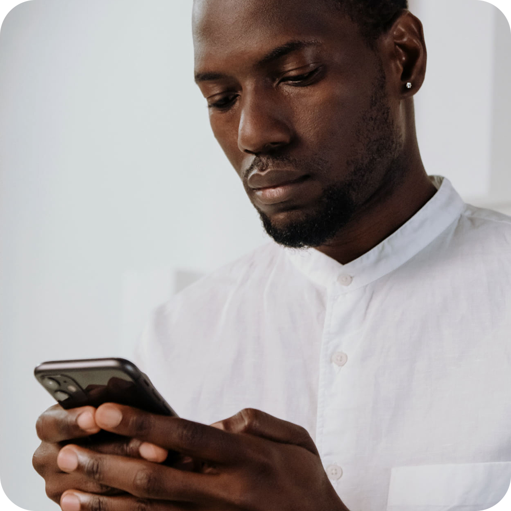 Man in a white shirt holding and typing on a smartphone