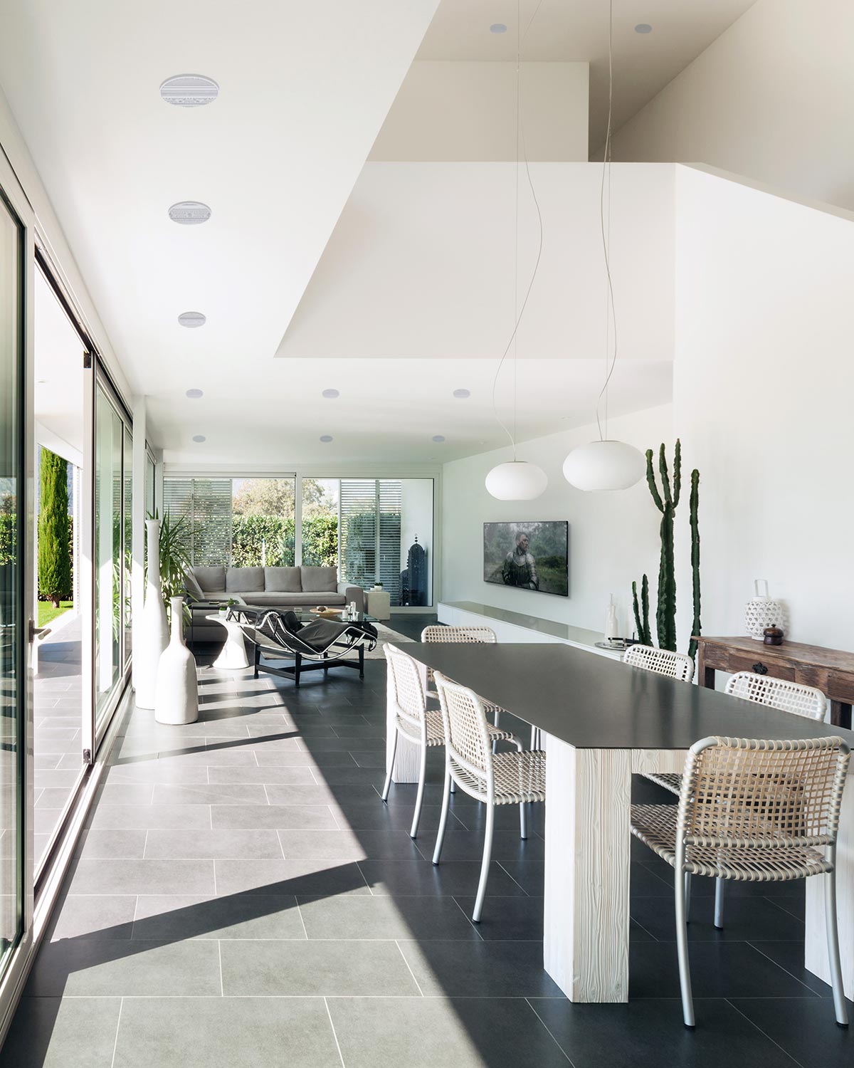 Bright dining room with a long table, woven chairs, and sliding glass doors