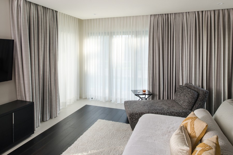 Lutron drapery track system in a high-end bedroom. Drapes are shut while soft white light filters through.