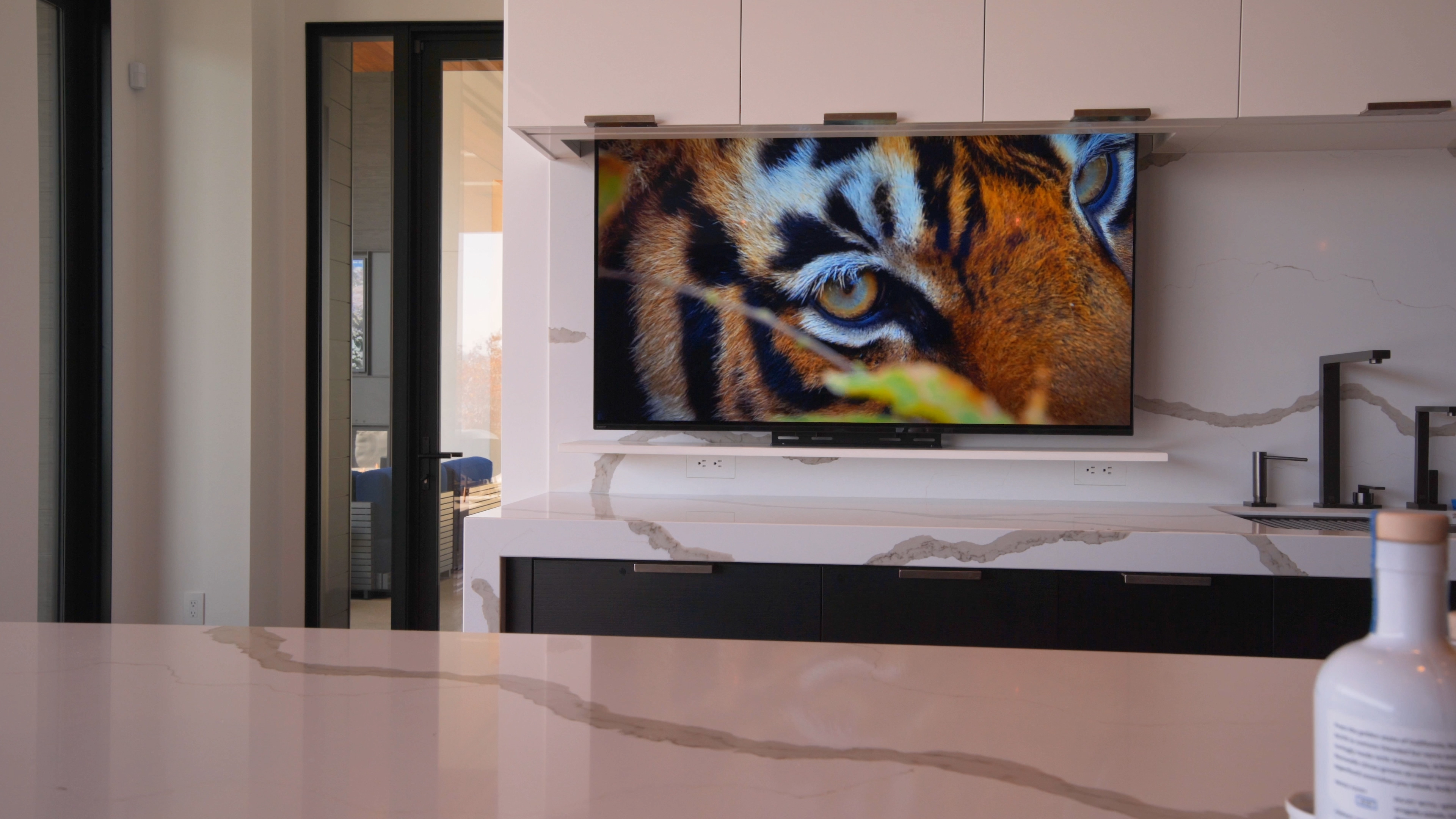 A close-up of a high-definition TV showing vibrant tiger imagery, mounted in a stylish kitchen area.