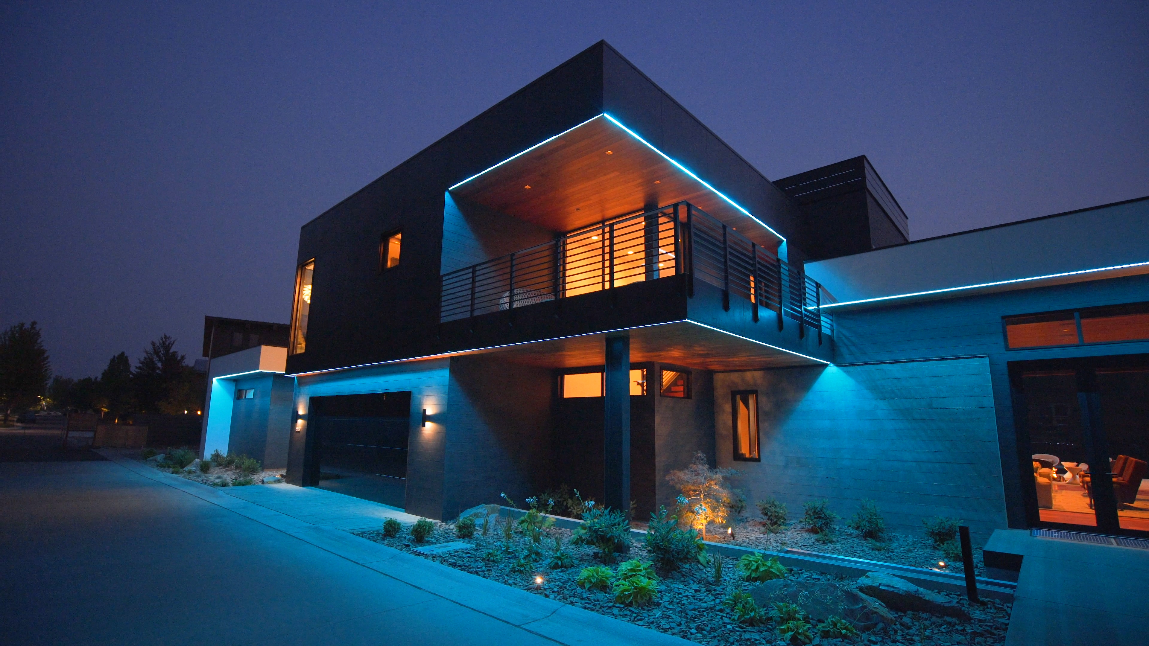 A contemporary home illuminated with striking blue LED lights, highlighting its architecture at night.