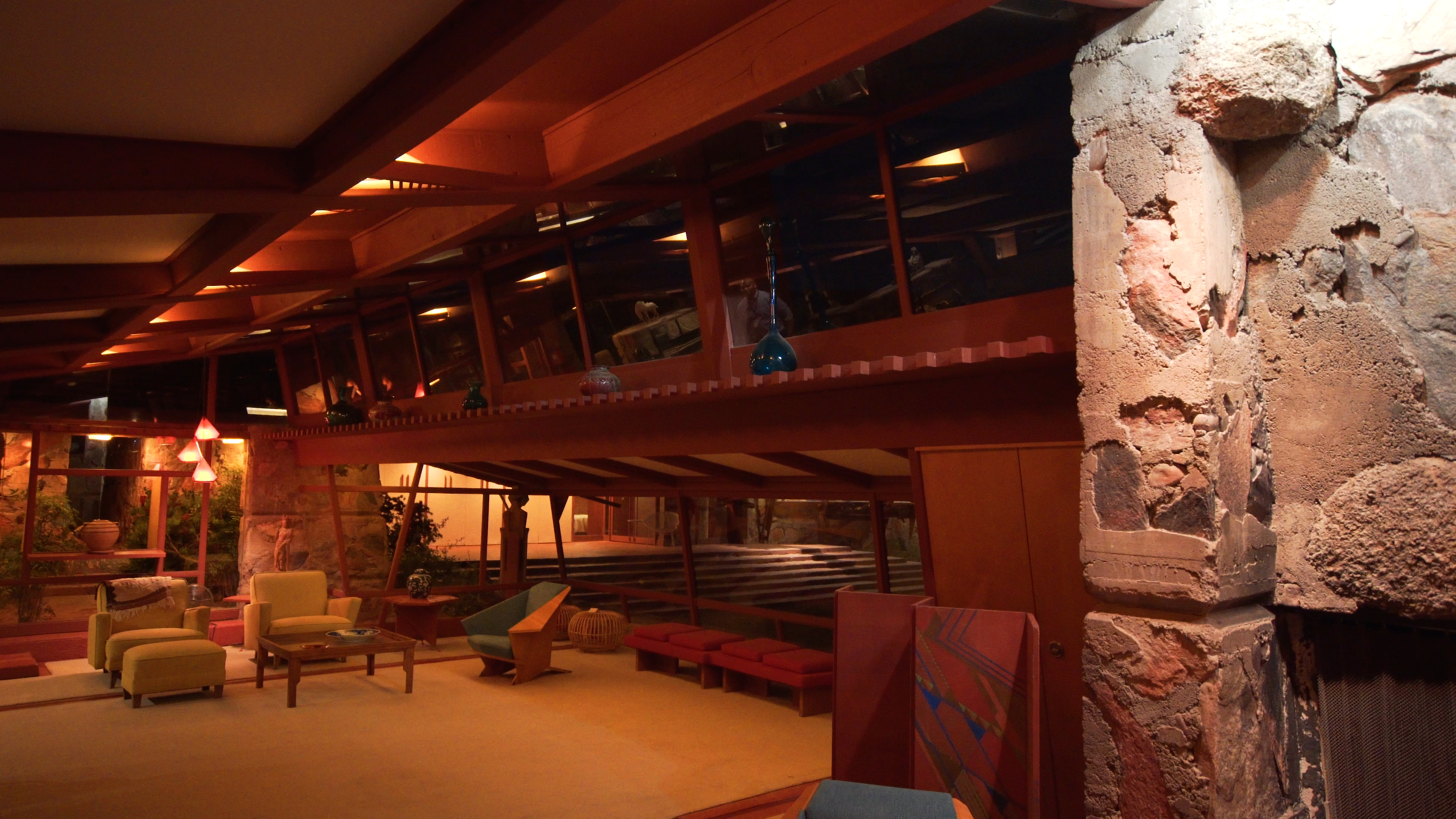 Interior living area at Taliesin West showing warm ambient LED light accentuating midcentury furniture and textured stone walls.