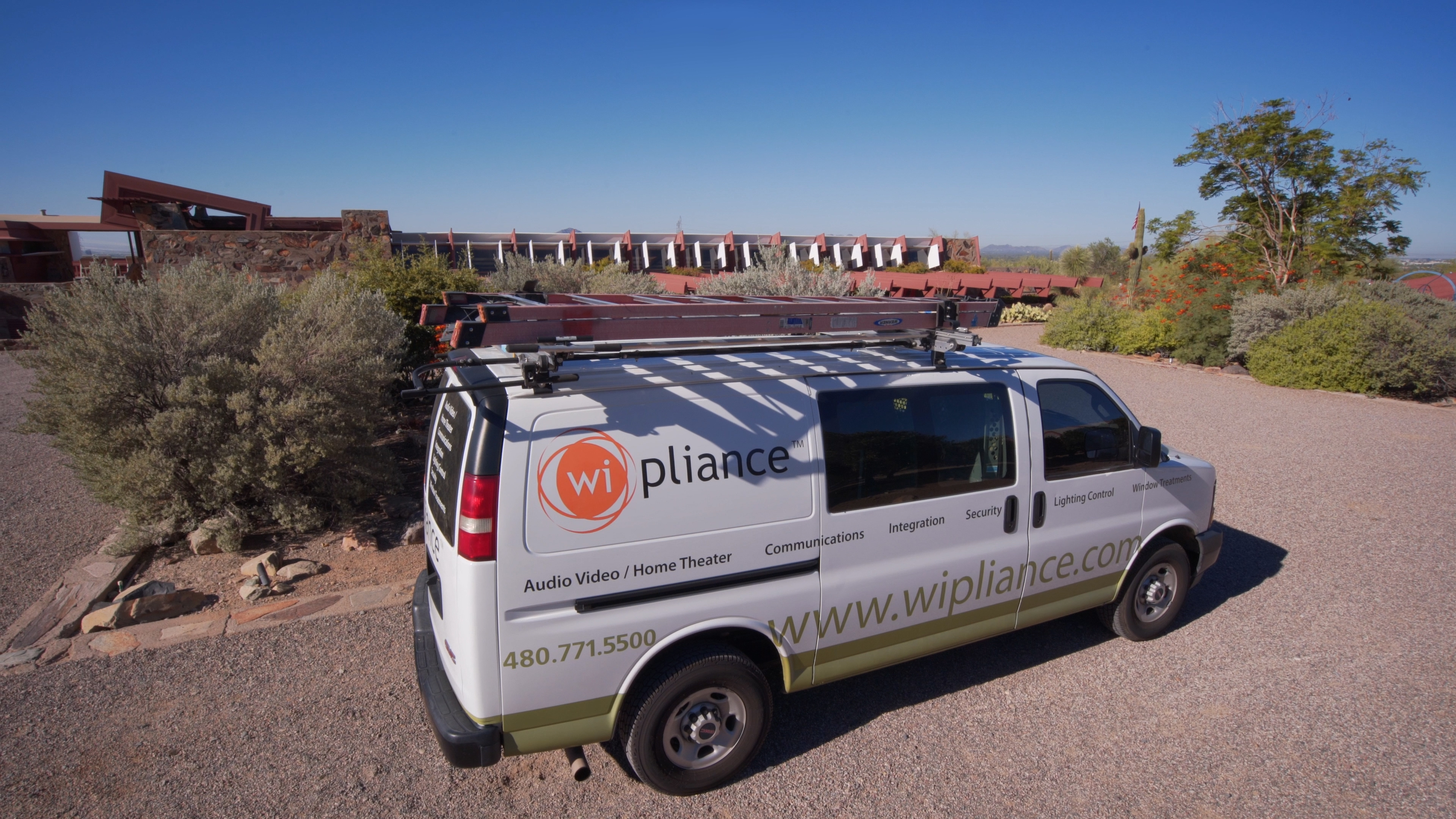 Wipliance service van parked on gravel driveway outside Taliesin West, framed by desert plants and Wright&rsquo;s stone walls.