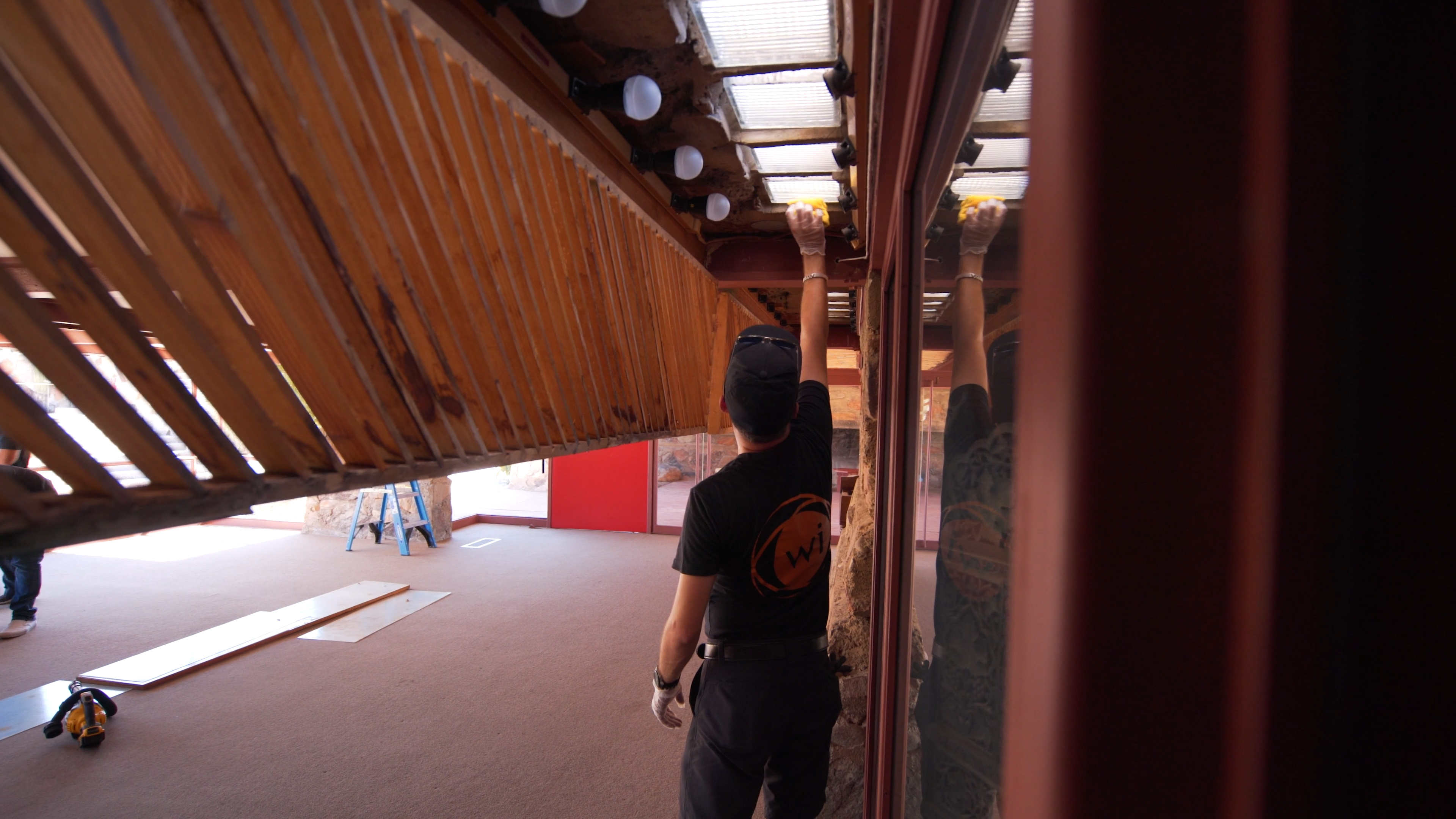  Technician wearing Wipliance logo shirt carefully installs LED lighting into historic interior fixture at Taliesin West.