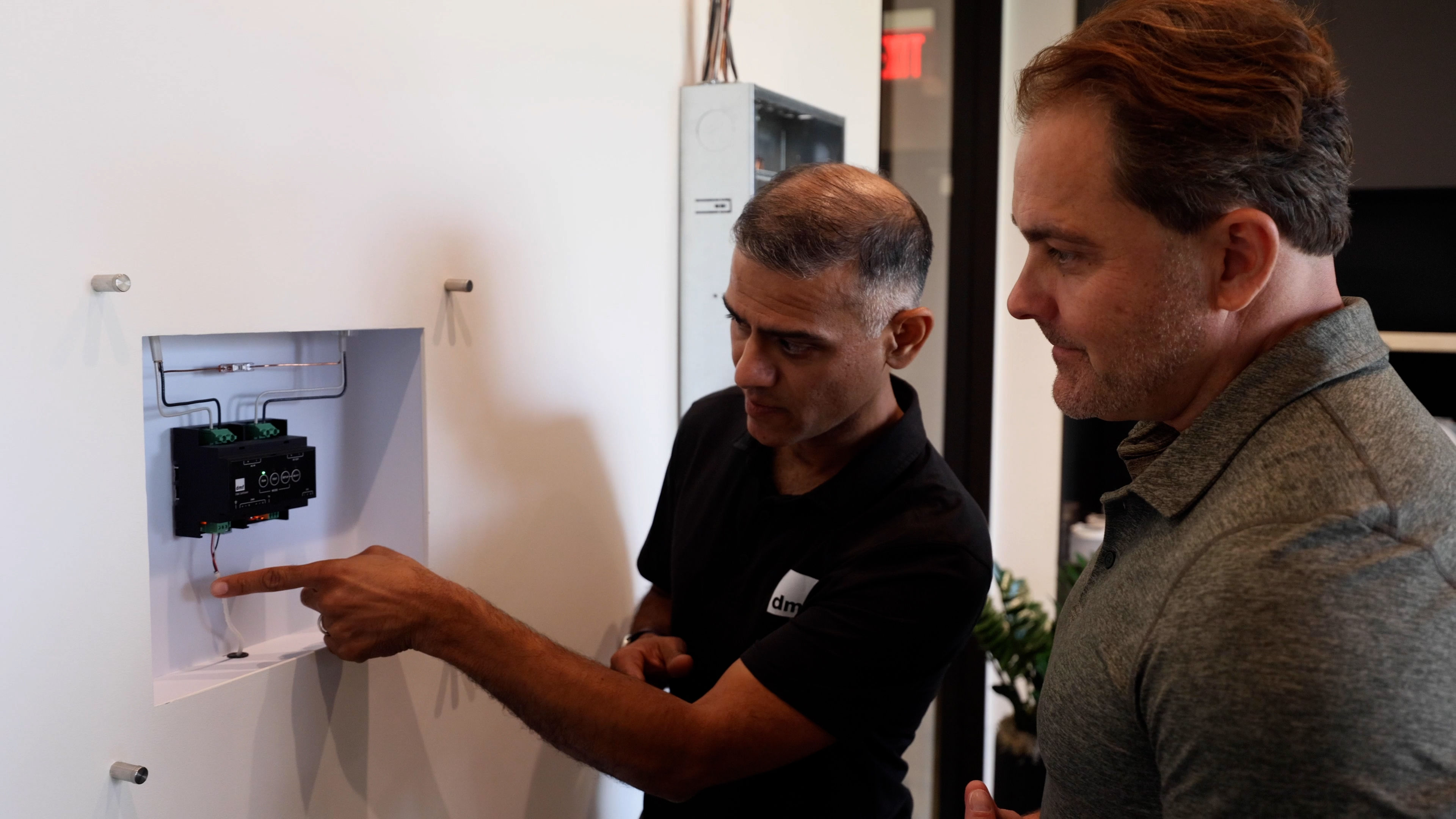 A technician explains the PhaseX DMX lighting control system to a client during an in-home consultation.