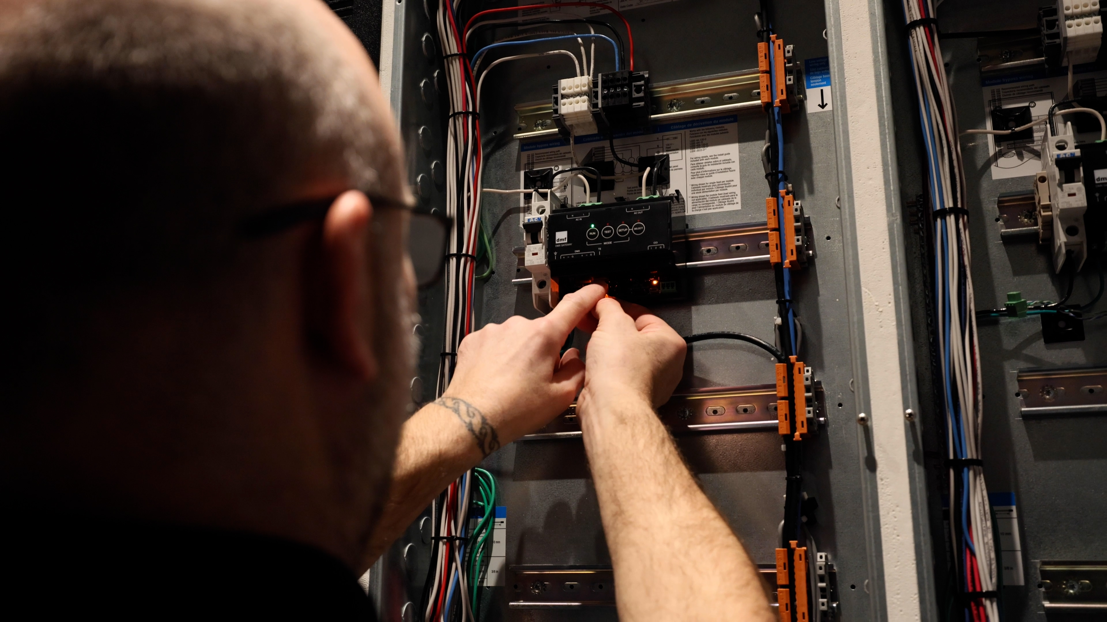 An installer connects the PhaseX gateway within an electrical panel, ensuring proper setup and integration.