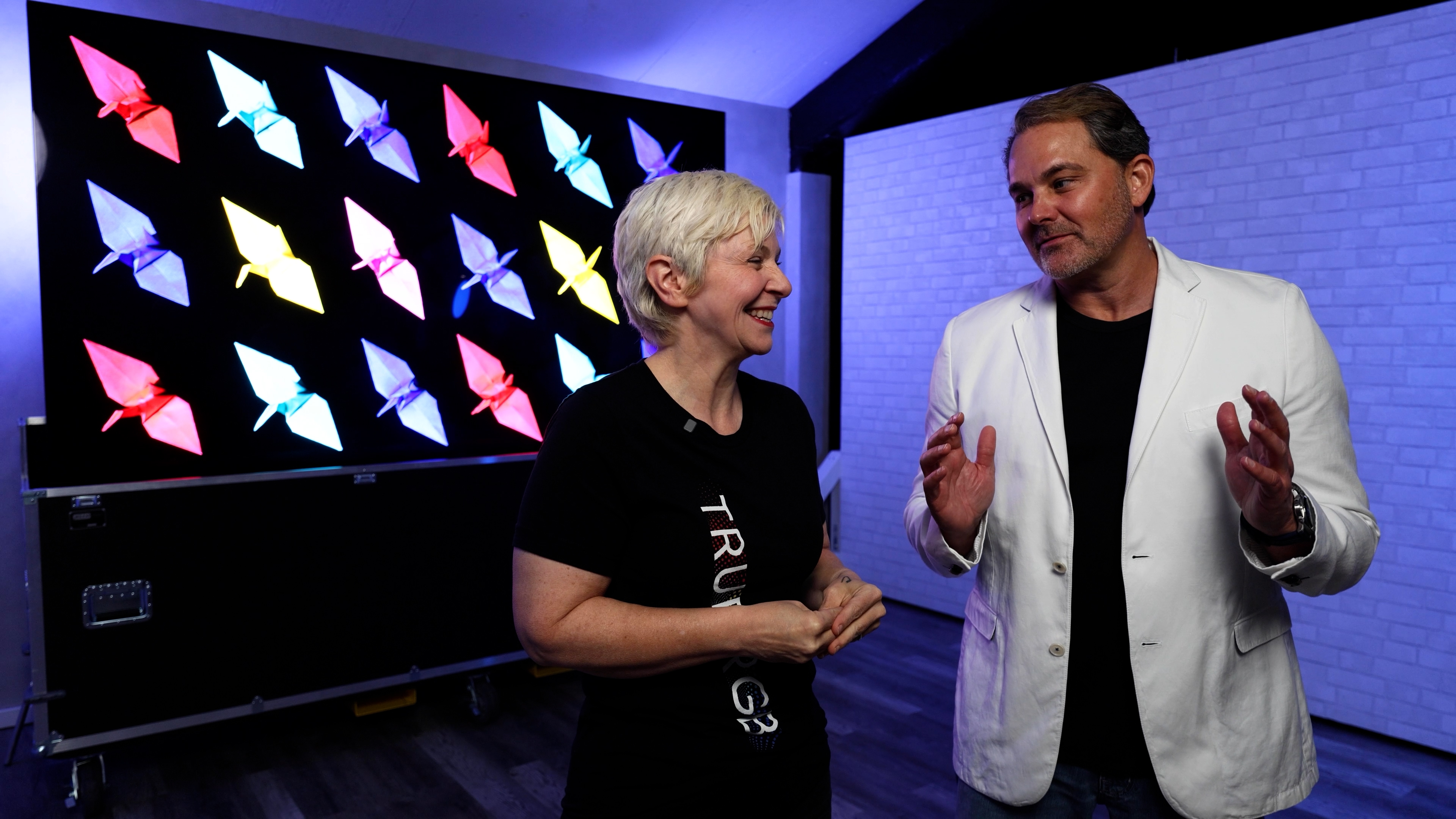 Two people adjusting and testing DMF lighting systems in a luxurious kitchen with subtle lighting accents.
