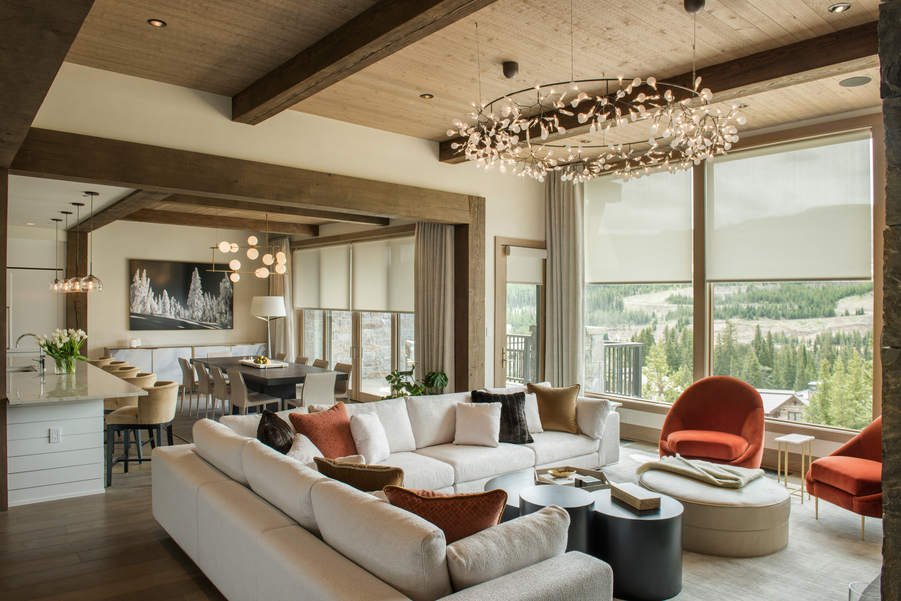 Modern living room with Lutron light-filtering motorized shades lowered over windows with a mountain view.