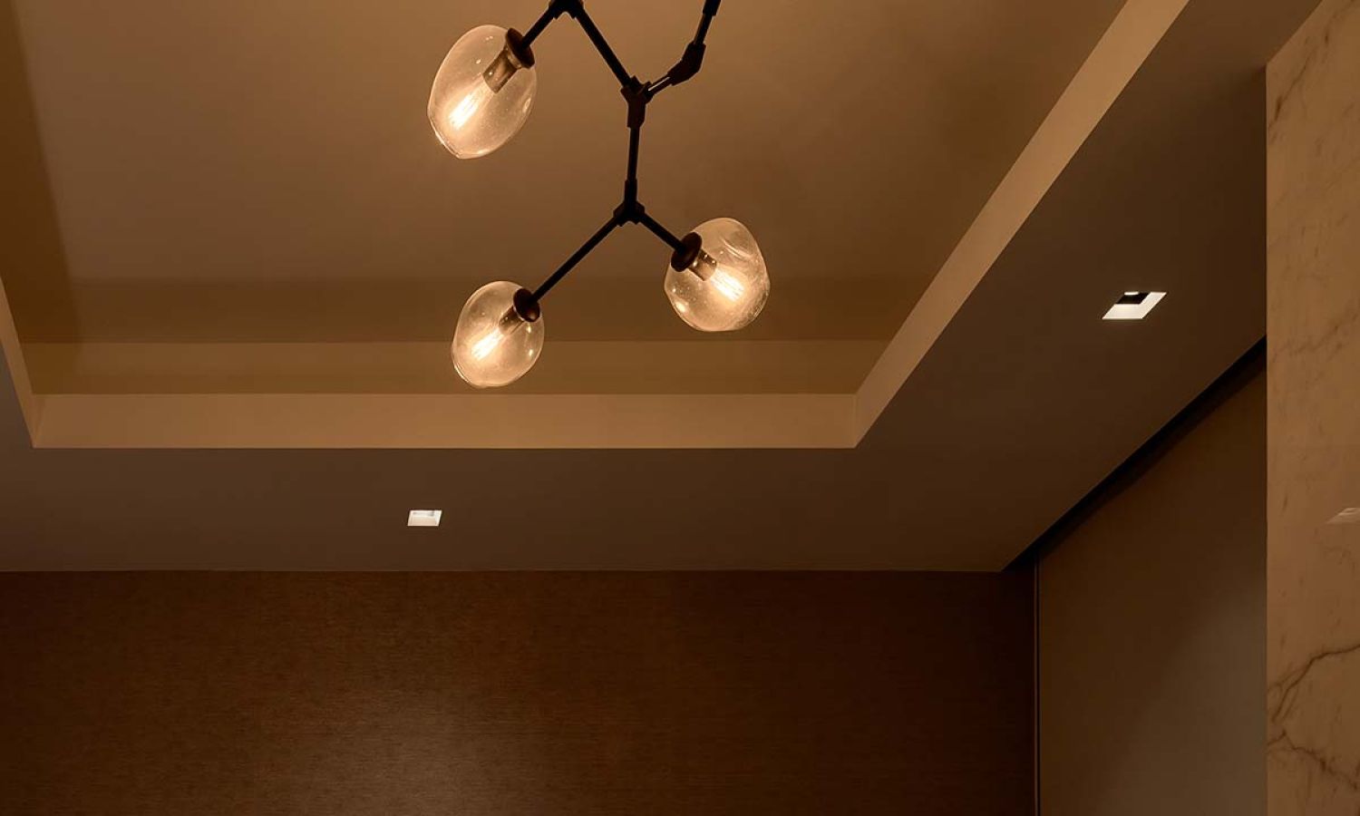 Ceiling with modern three-bulb light fixture and warm dim lighting