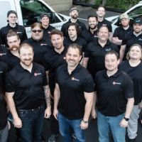 Wipliance and Obot Electric team members posing together in front of branded company vans