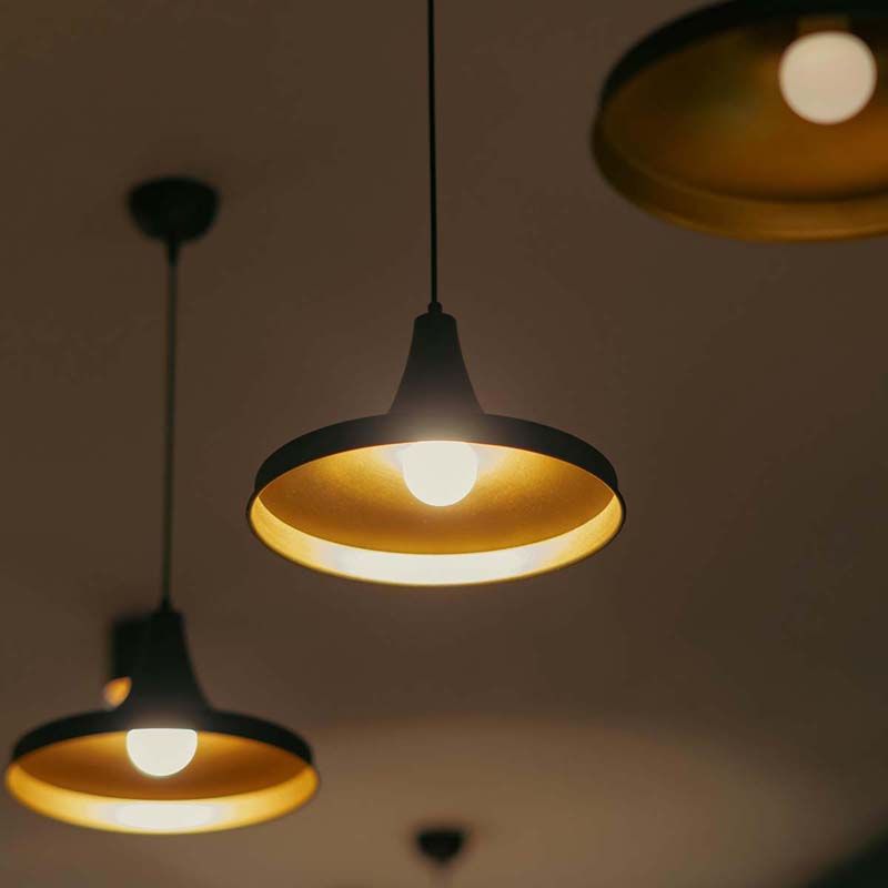 Close-up of black pendant lights with gold interiors, hanging in a minimalist space.