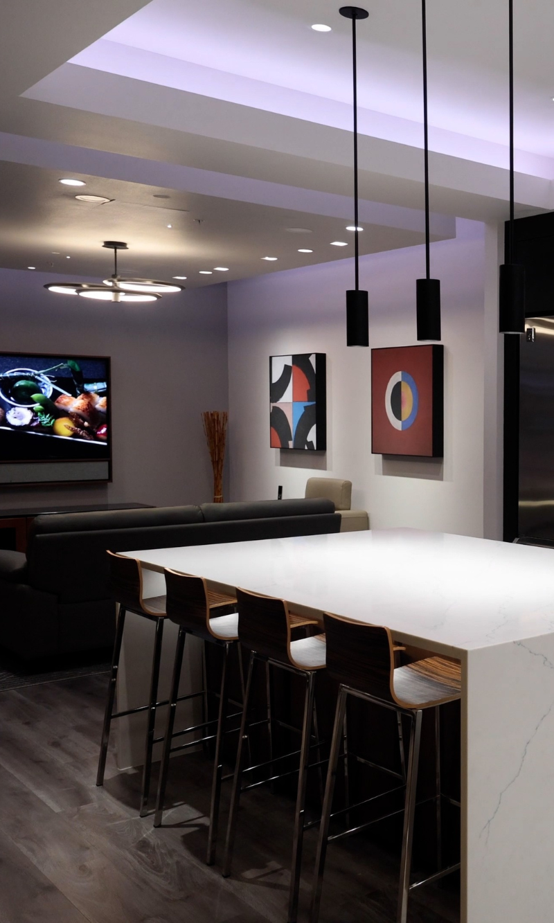 Modern living room with a stunning geometric ceiling design illuminated by DMF Lighting recessed fixtures, enhancing the architectural details.